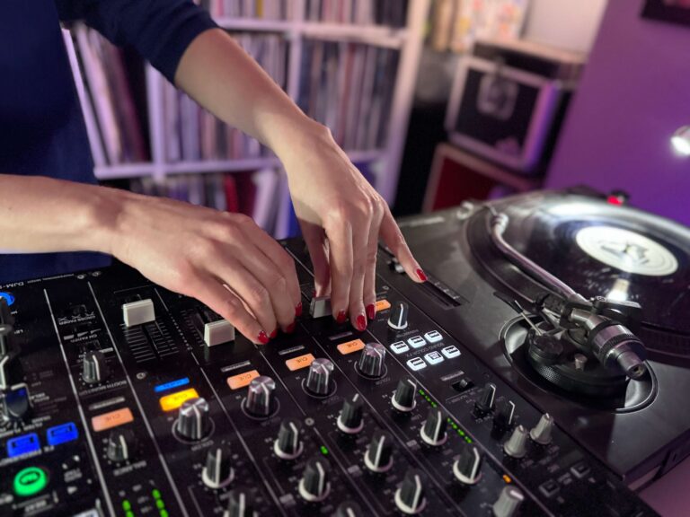 Hands mixing on a DJ mixer and turntables at Drop Studios
